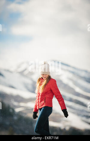 Ein junges Mädchen in einem roten Mantel und Wollmütze im Freien im Winter. Stockfoto