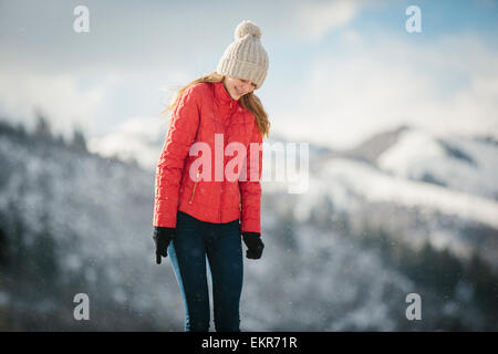 Ein junges Mädchen in einem roten Mantel und Wollmütze im Freien im Winter. Stockfoto