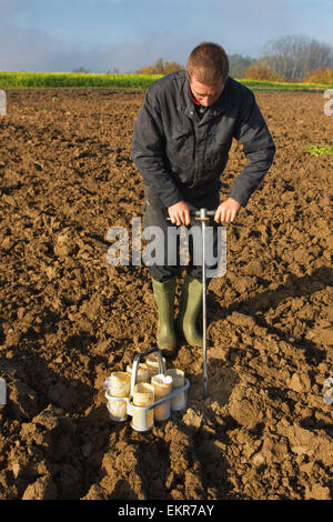 Forscher Bodentest durchführen, indem man manuelle Erde Kernproben aus Feld mit Metall corer Stockfoto