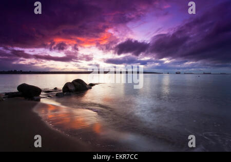 Der Sonnenuntergang, eine orange und lila Himmel spiegelt sich in ruhigem Wasser. Stockfoto