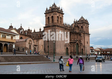 Peru, Cusco.  Junge Frauen gehen in der Plaza de Armas; Kathedrale im Hintergrund. Stockfoto