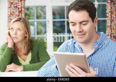 Unglückliche Frau am Tisch als Partner nutzt Digital-Tablette Stockfoto