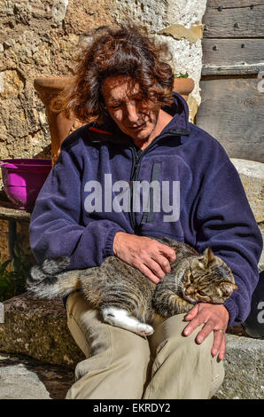 Frau sitzt auf den Stufen des Steintreppen streichelte eine braune gefleckte Katze kuscheln auf dem Schoß Stockfoto