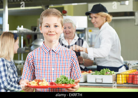 Männliche Schüler mit gesundes Mittagessen In der Cafeteria der Schule Stockfoto