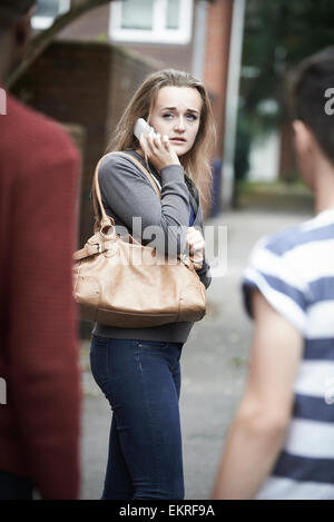 Teenager-Mädchen auf dem Handy fühlen eingeschüchtert, als sie Spaziergänge nach Hause Stockfoto