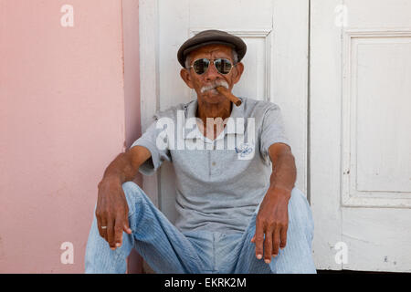 Kubanische Mann mit Sonnenbrille, raucht eine Zigarre in einem Hauseingang Stockfoto