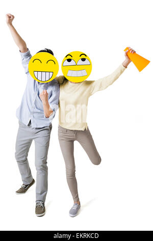 Junges Paar mit zwei happy Emoticon Gesichtern vor der ihre Gesichter jubeln Stockfoto