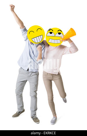 Junges Paar mit zwei happy Emoticon Gesichtern vor der ihre Gesichter jubeln Stockfoto