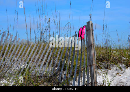 Rosa Strand Schuhe Trocknen auf einem abgenutzten verwitterten Zaun, inmitten der weißen Sanddünen ein Golf von Mexiko, Florida beach Stockfoto