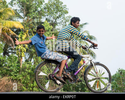 Zwei jungen auf einem Fahrrad an den Ufern der Backwaters Kumarakom, Kerala Indien Stockfoto