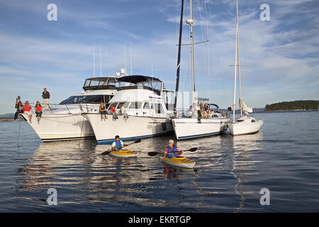 Kajakfahrer pass eine Flottille von Motorboote und Segelboote Autobahnabfahrt Sidney Insel; Sidney, British Columbia, Kanada Stockfoto