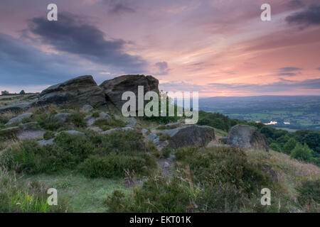 Hell, bunt, orange, rote Himmel bei Sonnenuntergang über Felsblöcke auf einem Felsvorsprung mit Blick auf Wharfedale - (Otley Chevin, West Yorkshire, England, UK). Stockfoto