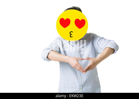 Junger Mann mit einem romantischen Emoticon Gesicht vor seinem Gesicht Stockfoto