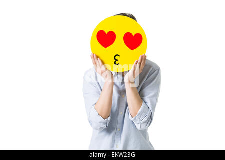 Junger Mann mit einem romantischen Emoticon Gesicht vor seinem Gesicht Stockfoto