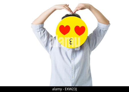 Junger Mann mit einem romantischen Emoticon Gesicht vor seinem Gesicht Stockfoto