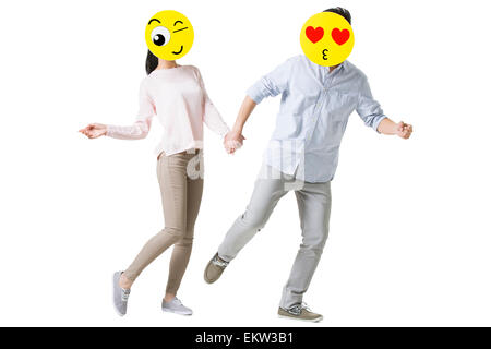 Junges Paar mit Cartoon Emoticon steht vor den Gesichtern Stockfoto