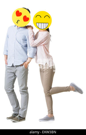 Junges Paar mit Cartoon Emoticon Gesichtern vor den Gesichtern Stockfoto