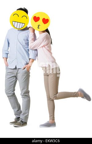 Junges Paar mit Cartoon Emoticon Gesichtern vor den Gesichtern Stockfoto