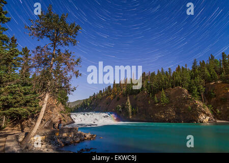 Die Stars von den nördlichen Himmel Kreisen Sterne Wanderwege über Bow Falls am Bow River im Banff, Alberta. Eine schwache Moonbow kann sein Stockfoto