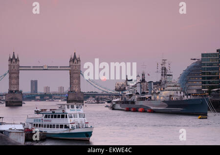 Der Himmel dreht lila über London Tower Bridge und die Boote auf der Themse wie der Mond aufsteigt. Stockfoto