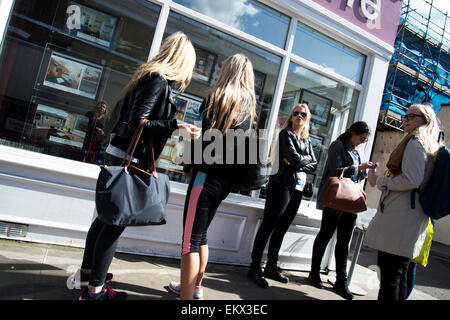 Hackney Frühjahr 2015. Broadway-Markt. Zwei junge Frauen Prüfung Immobilienmakler und Blondinen - Fotos von Häusern Stockfoto