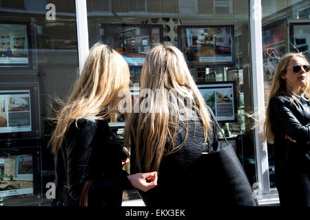 Hackney Frühjahr 2015. Broadway-Markt. Zwei junge Frauen Prüfung Immobilienmakler und Blondinen - Fotos von Häusern Stockfoto