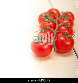 frische Kirschtomaten auf einem Cluster über rustikalen Holztisch Stockfoto