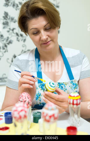 Frau malt die Ostereier mit einem Pinsel Stockfoto