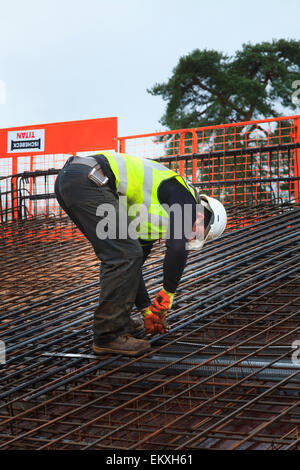 Bauarbeiter Betonstahl vor dem Gießen des Betons auf einem Geschäftshaus Dach zu binden. Stockfoto