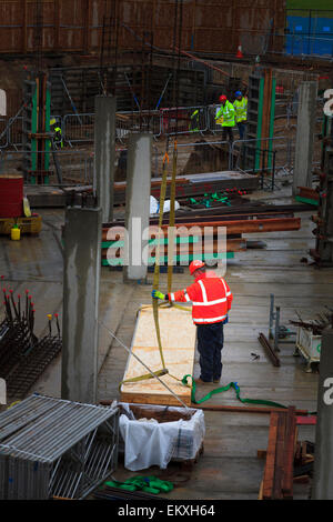 Bau Arbeiter anhebende Riemen am Kran heben auf der Baustelle. Stockfoto