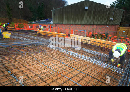 Bauarbeiter Betonstahl vor dem Gießen des Betons auf einem Geschäftshaus Dach zu binden. Stockfoto