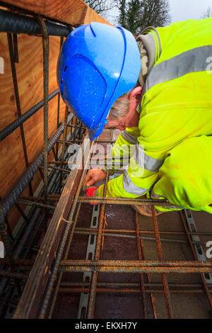 Bauarbeiter Betonstahl vor dem Gießen des Betons auf einem Geschäftshaus Dach zu binden. Stockfoto