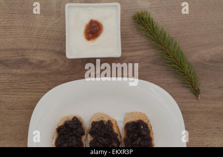 Marmelade auf Scheiben Brot und Joghurt und Stift hinterlässt auf Holz Hintergrund Stockfoto