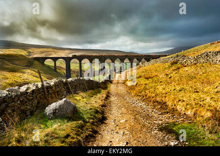 Zug mit Protokollen kreuzt nachbarschaftlich Gill Viadukt in der Nähe von Dent. Die Settle Carlisle Railway ist aus der Pennine Bridleway gesehen. Stockfoto