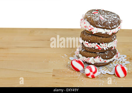 Schokoladen-Whoopie Pies mit gestreiften Weihnachtsplätzchen auf Spitze Schneeflocke Deckchen gestapelt. Stockfoto