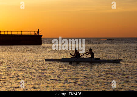 Hampton, Kent, UK. 14. April 2015: UK Wetter. Sonnenuntergang am Hampton in der Nähe von Herne Bay in Kent als Angler Fische vom Pier, Ruderer und ein Schnellboot machen das Beste aus den letzten Strahlen des Lichtes nach einem herrlichen heißen Tag mit mehr gute Wettervorhersage für Mittwoch Stockfoto