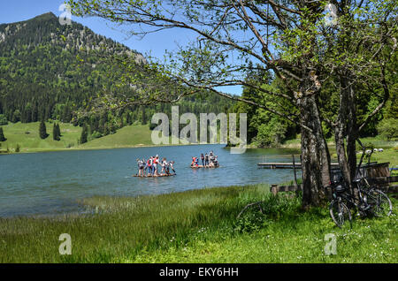 Eine Gruppe von Touristen mit Flößen des romantischen Spitzingsee umringt von dunklen Bergwald ist Bayerns größte Bergsee Stockfoto