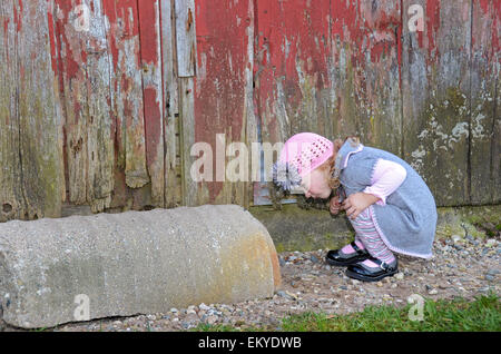 Neugierige kleine Mädchen auf der Suche in einem Betonrohr von alten Scheune. Stockfoto