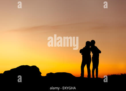 Silhouetten von Mutter und Tochter an den wunderschönen Sonnenuntergang. Einbruch der Dunkelheit. Sommerlandschaft Stockfoto