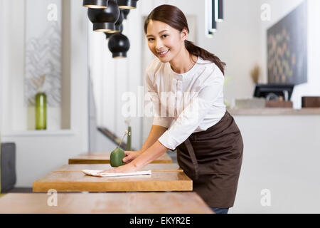 Junge Kellnerin wischen Tisch Stockfoto