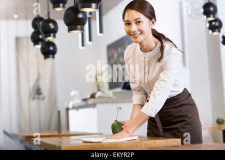 Junge Kellnerin wischen Tisch Stockfoto