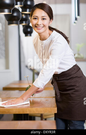 Junge Kellnerin wischen Tisch Stockfoto