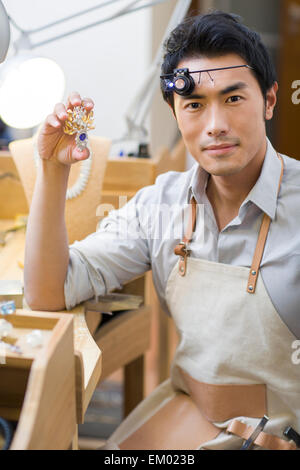 Männliche Juwelier hält eine Brosche Stockfoto