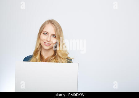 Glücklich lächelnde junge Frau zeigt leere Schild Stockfoto