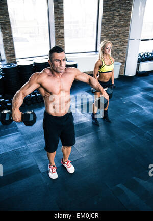 Muskulöser Mann und Fit Frau Aufhebung Hanteln im Fitnessstudio Stockfoto