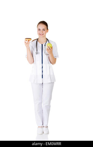 Diätassistentin mit süßen Krapfen und frischen gesunden grünen Apfel. Stockfoto