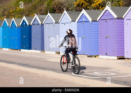 Bournemouth, Dorset, UK 15. April 2015. Radfahren entlang der Promenade vorbei an Schattierungen von lila blau Strandhütten in Boscombe Bournemouth im April Credit: Carolyn Jenkins/Alamy Live News Stockfoto