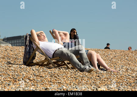 Sonnenanbeter sonnen sich an einem glühenden Tag in Brighton Beach, City of Brighton & Hove, East Sussex, Großbritannien. 15. April 2015 Stockfoto