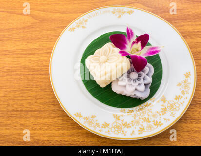 Gelb und schwarz geschnitzten Mochi-Kuchen auf Thai Bananenblatt in ein weißes Gold Modellplatten Stockfoto