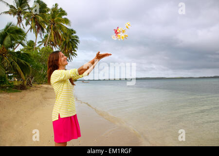 Junge Frau am Strand werfen Blumen in der Luft, Ofu Insel Tonga Stockfoto